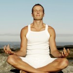 Man Meditating on a Rock at the Beach